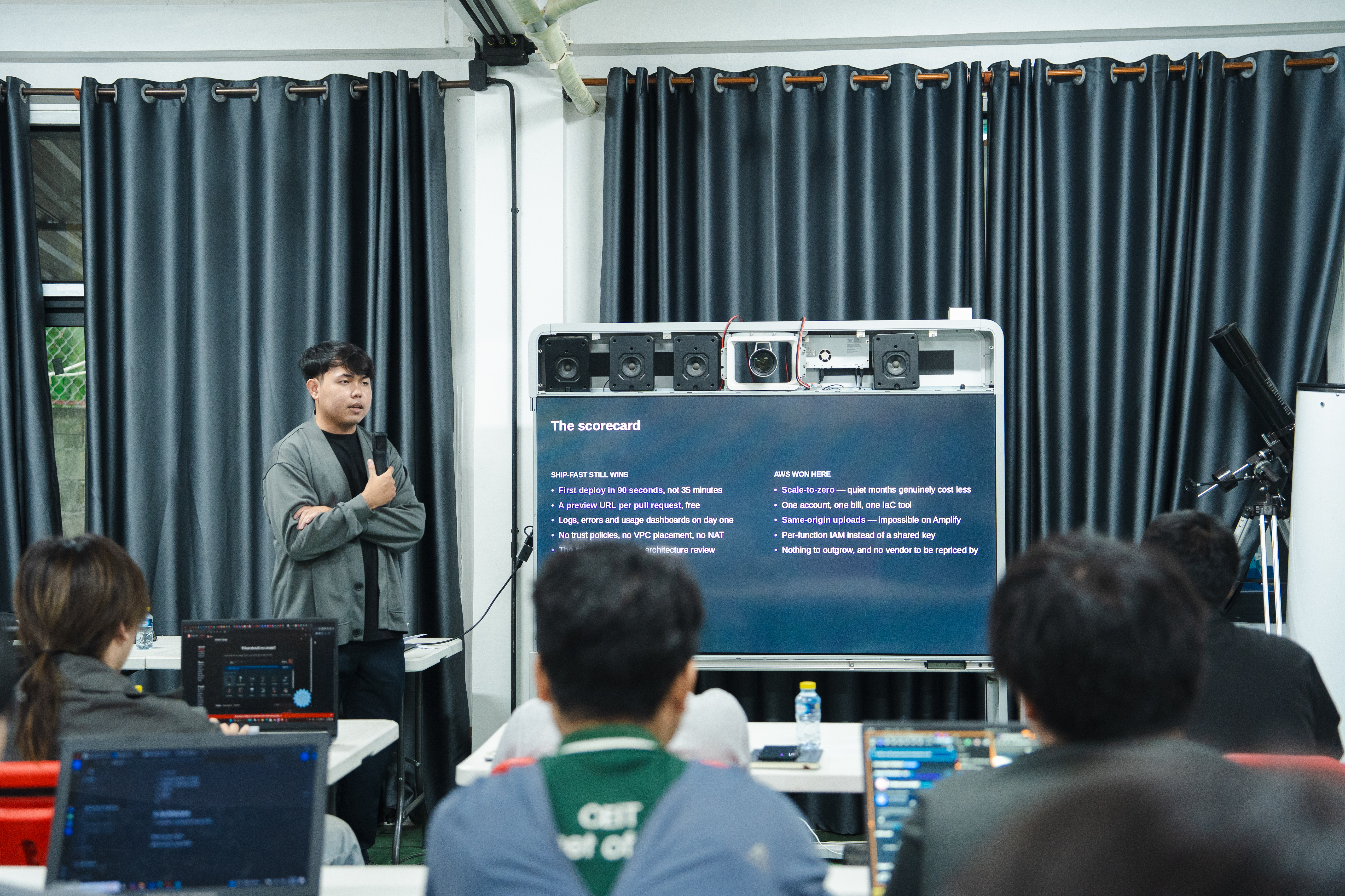 Ketsadaphone presenting to the room, with attendees and laptops in the foreground