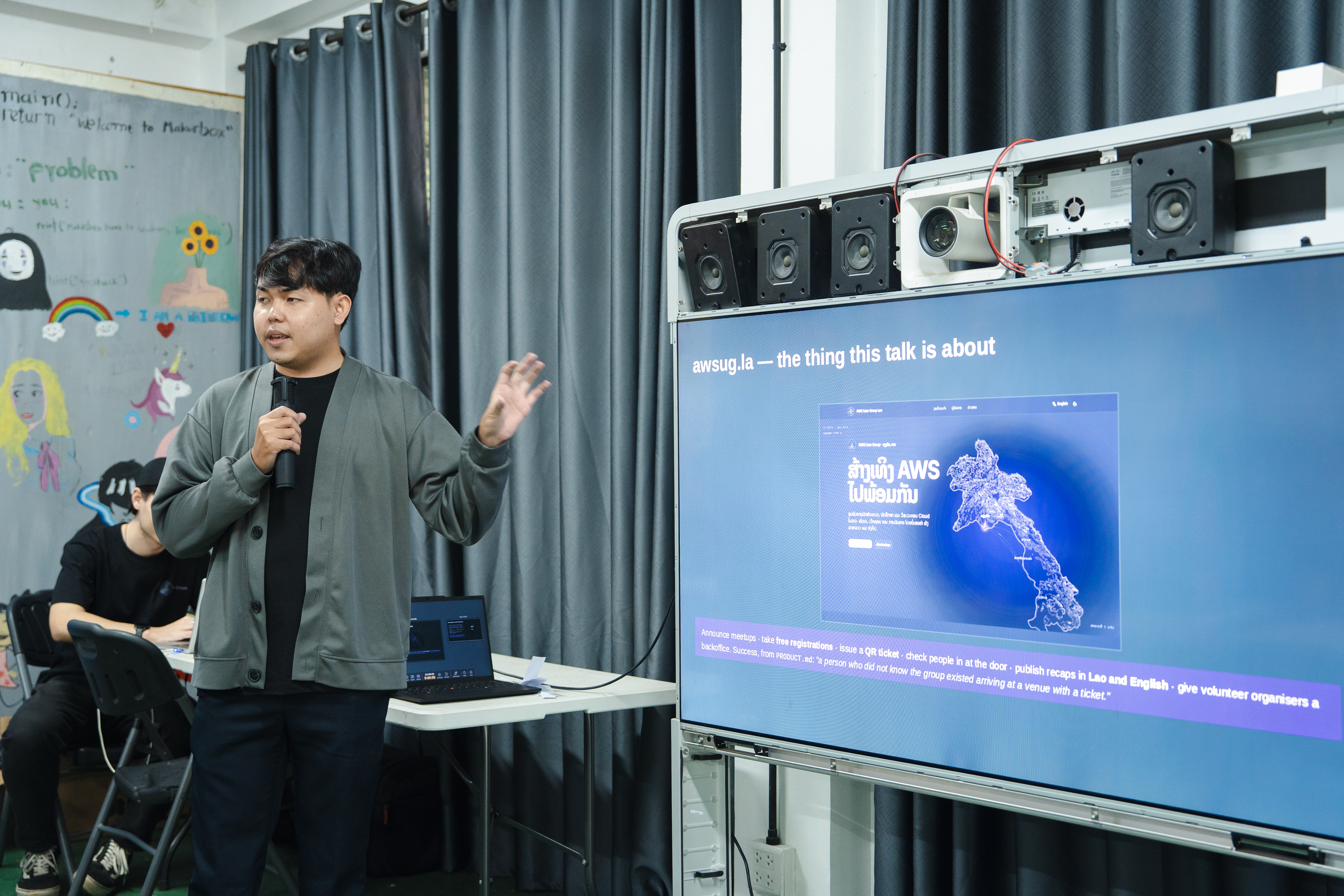 Ketsadaphone gesturing toward the audience while presenting